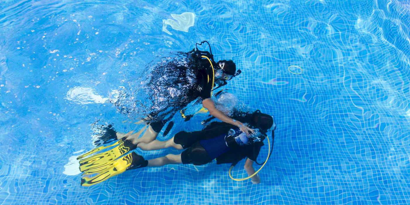 Diving baptism of a group of kids in a swimming pool, accompanied of them instructors.